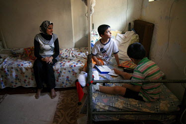 Thirty four year old Jihan with her sons Ahmed and Mohammad, aged five and seven, play in their one rooim home in the Lavrio refugee camp.  They left Damascus with Jihan's husband Ashraf, to escape th...