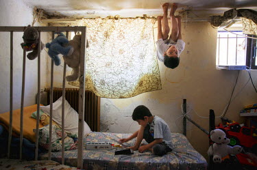 Ahmed and Mohammad aged five and seven play on their bed in the Lavrio refugee camp.  They left Damascus with Jihan's husband Ashraf, to escape the conflict. Jihan is nearly blind, both husband and wi...