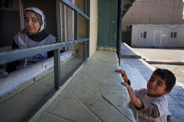 Thirty four year old Jihan sits in a cafe at the Lavrio refugee camp while her son Ahmed tries to get her attention.  They left Damascus with Jihan's husband Ashraf, to escape the conflict. Jihan is n...