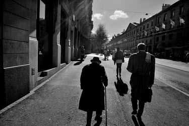 An elderly businessman walks along the Corraterie, one of the main banking streets in Geneva, including UBS at left.