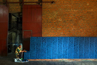 A worker at the Savonnerie Industrielle de Butembo (SAIBU) stacks blocks of its main product, blue bars of soap. Bad roads and insecurity means the company generally can only sell its products locally...