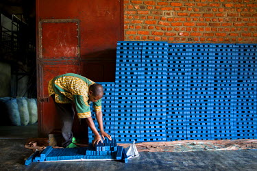 A worker at the Savonnerie Industrielle de Butembo (SAIBU) stacks blocks of its main product, blue bars of soap. Bad roads and insecurity means the company generally can only sell its products locally...