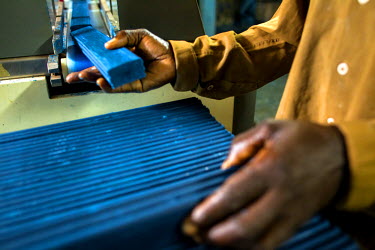 A worker at the Savonnerie Industrielle de Butembo (SAIBU) stacks blocks of its main product, blue bars of soap, as they come off the production line. Bad roads and insecurity means the company genera...