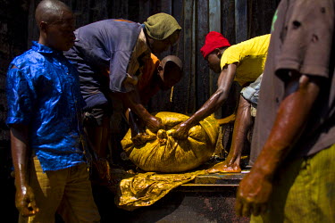Workers at the Savonnerie Industrielle de Butembo (SAIBU), a soap factory, drag sacks of palm oil, a key ingredient in the manufacture of soap, into the facility. Bad roads and insecurity means the co...