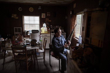 Jesse Boggess, armed with a rifle, sits at the window of his home. He was awarded 16 different medals during service in the Vietnam War from 1969 to 1970, including a Medal of Honor. Now he lives by h...