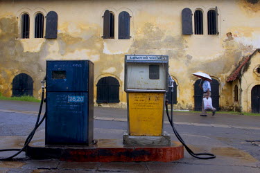A man walks past a former Dutch colonial-era warehouse of the East India Company and old a pair of old fuel pumps.