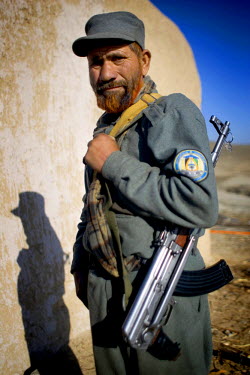 A member of the Afghan National Police (ANP) guards a Shura or consultation between the Governor of Kandahar and local villagers.