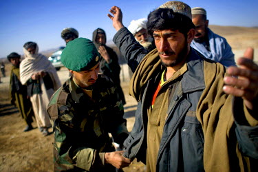 A soldier from the Afghan National Army (ANA ) searches a man before a Shura or consultation between the Governor of Kandahar, Assadullah Khalid, and local villagers.