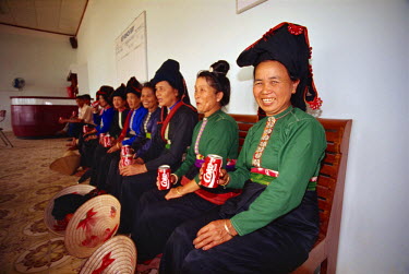 Hill tribe women in their daily costume get their first taste of Coca Cola while waiting to see off a local dignitary at Dien Bien Phu's rudimentary airport. The official presented them all with the d...