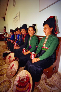 Hill tribe women in their daily costume get their first taste of Coca Cola while waiting to see off a local dignitary at Dien Bien Phu's rudimentary airport. The official presented them all with the d...