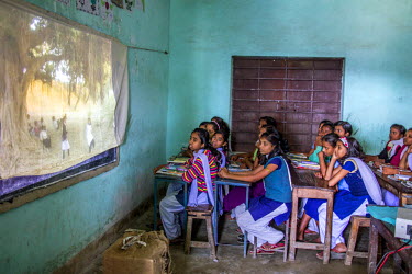 Students attending an anti-child trafficking lecture watch a film projected onto a sheet.