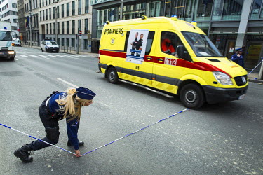 A policewoman lets an ambulance through police lines on the Rue de la Loi / Wetstraat in the centre of Brussels near the headquarters of the European Commission, the scene of a terrorist bombing in th...