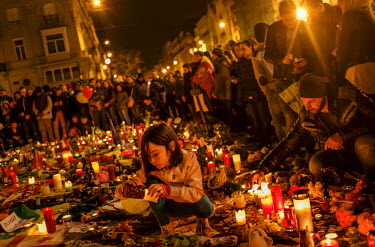 A girls crouches amongst tributes and flowers in front of the Bourse (Stock Exchange) in central Brussels to pay their respects to the victims of the Brussels terrorist attacks and to show solidarity....