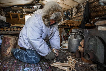 Ion Maxsimovic prepares kindling for the wood stove in his winter hunting lodge. He will get up numerous times in the night to keep the fire burning as temperatures in the region can get as low as min...