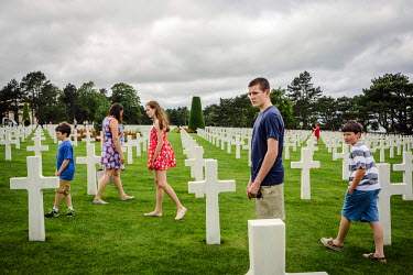 An American family walk among the head stones while visiting the Normandy American Cemetery.