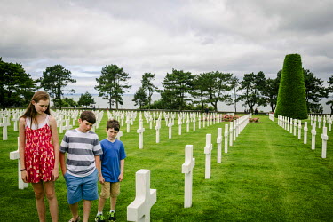 An American family walk among the head stones while visiting the Normandy American Cemetery.