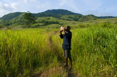 Antipas Kiriwang blows a conch shell (a traditional form of communication and warning in Papuan traditional societies).