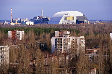 Abandoned housing in Pripyat, a ghost town left deserted by the nuclear disaster at the adjoining Chernobyl nuclear site. In the background is a new confinement structure called 'the arch' which is be...