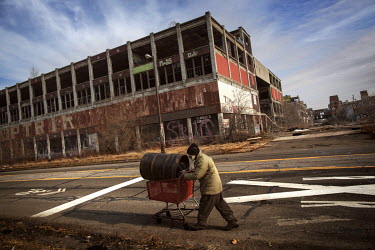 Ronnie Bowlson (58) pushes a scavenged barrel past the ruins of the former Packard Automotive Plant, once a factory where once luxury Packards were made by the Packard Motor Car Company and later by t...