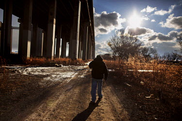 John Bryant (35) walks beneath a concrete freeway in Delray beside the Rouge River. The area is cluttered with chemical factories and oil refineries. Bryant says: 'This area looks like a dump. People...