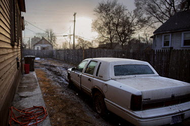 A Lincoln Town Car parked on a muddy pathway between two houses.Hard.Landis a journey through rust belt and blue collar America to meet the people struggling to keep the 'American Dream' alive: middle...