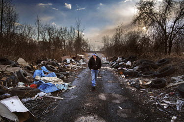 John Bryant (35) walks through a rubbish strewn road in Delray beside the Rouge River. The area is cluttered with chemical factories and oil refineries. Bryant says: 'This area looks like a dump. Peop...
