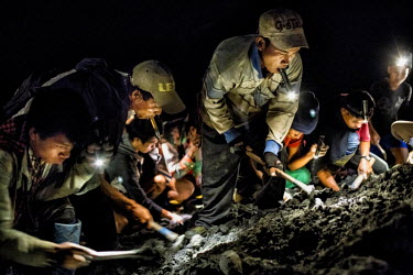 Illegal miners working by torchlight, going over a pile of company mining waste, looking for jade.