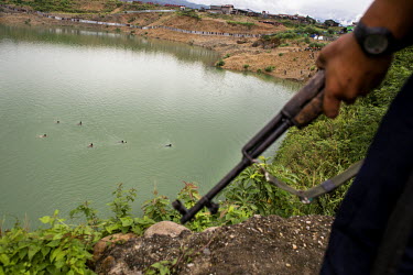 A group of illegal jade miners swim across the water as they try to escape an arrest by police and the military at a jade mine. Military officials say the miners are illegal and endangering a school l...