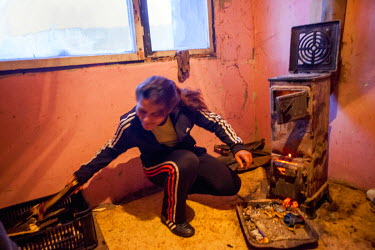 Milena, mother of four daughters and a son, stokes a wood burning stove in the flat in the Lunik IX housing complex given the family when the block they lived in was demolished. The family consist of...