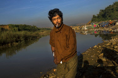 A drug addicted jade miner walks, with a needle stuck in his arm, near a 'shooting gallery'. Heroin is almost openly available in Hpakant with jade miners lining up for a shot which is as cheap as 2,0...