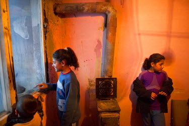 Siblings stand around the wood burning stove in their family flat in the Lunik IX housing complex. The accommodation was given the family when the block they lived in was demolished. The estate is alm...