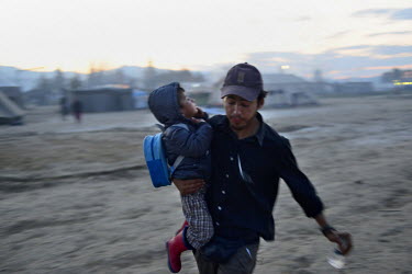 A man runs holding a child as a group of refugees clash with Greek police at the refugee camp of Idomeni at the Greek-Macedonian border. Clashes erupted in May 2016 with refugees protesting against the closure of the border. Idomeni refugee camp is housing around 10,000 refugees have been stranded since Macedonia decided to close its border with Greece in March 2016, blocking the route to the North of Europe for hopeful migrants and refugees.