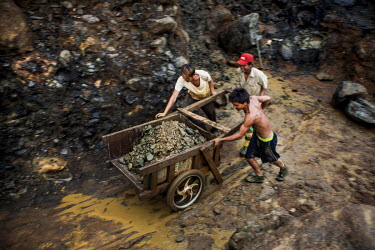 A team of small-scale miners cart away the spoil from a jade mine. Some miners work alone while some like the young men here work in a team in a small plot of land that is owned by their 'Lao-ban' (me...