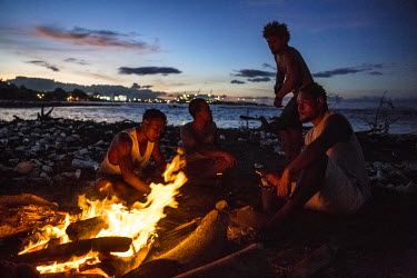 Young men sit by the fire at a beach in Lord Howe Settlement, a district of the capital Honaria populated by people from Ontong Java Atoll (AKA Lord Howe Atoll), a Polynesian outlier of the Solomon Is...