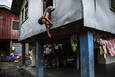 Monica, 12, hanging out of a window from a house in Lord Howe Settlement, a district of the capital Honaria populated by people from Ontong Java Atoll (AKA Lord Howe Atoll), a Polynesian outlier of t...