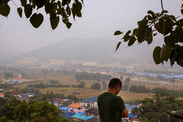A view of the town of Mong La in the morning mist with a man standing in the foreground.  The town of Mong La on the Burma - China border in western Burma (Myanmar) is technically in Burma but relies...