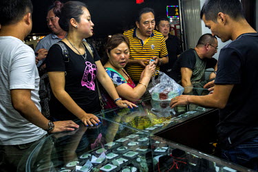 A group of Chinese tourists inspect items for sale in a shop in Mong La. The men buy bottles of tiger wine (made by infusing tiger bones and Chinese herbs in rice wine for up to 8 years) while the wom...