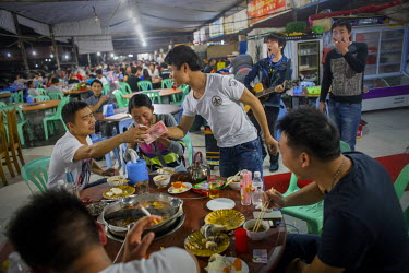 A group of Chinese tourists drink and dine at a restaurant in Mong La. Different kinds of live animals ranging from snakes and pangolins to turtles and others are kept in cages in front of the wildlif...