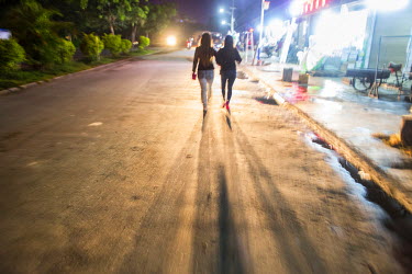 Two sex workers walk along a street in the red light district near Mong La's animal market at night.  The town of Mong La on the Burma - China border in western Burma (Myanmar) is technically in Burma...