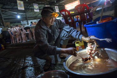 A man wearing a head torch cuts up a chicken in a yard behind a food court in the town of Mong La.  The town of Mong La on the Burma - China border in western Burma (Myanmar) is technically in Burma b...