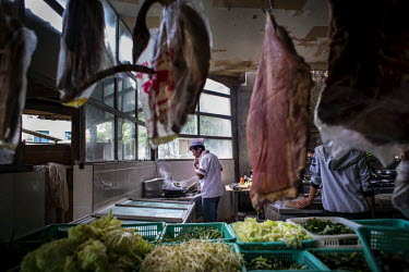 A cook tastes a dish in a kitchen at a restaurant in Mong La. Different kinds of live animals ranging from snakes and pangolins to turtles and others are kept in cages in front of the wildlife restaur...