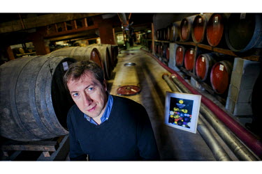 Bruno Cazes, the director of winemakers L'Etoile, in the company's cellars with a framed print of their new label designed by cartoonist Seb.