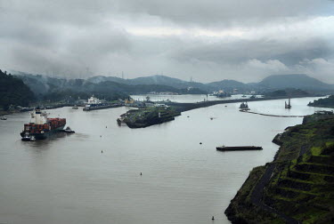 On the left ships use the Panama Canal's original locks while on the right dredges create a new channel during construction work for the Panama Canal Expansion. When complete, 26 June 2016, ships spec...