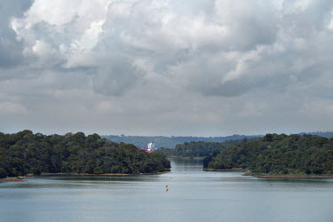 A container ship traverses a route through the artificial lake Gatun which links the Panama canal and supplies water to its locks.