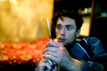 At his home in St Petersburg a drug users prepares a syringe, containing a heroin solution, for injection.