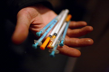 An injecting drug user holds a handful of used needle at a needle exchange point.