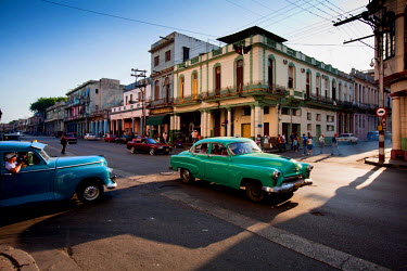 Classic American cars, mostly used as taxis, drive along Havana's streets.