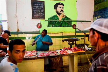 A portrait of Che Guevara painted on a wall behind a butcher's stall.