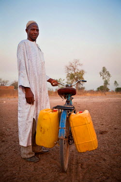A man collecting water carried in jerry cans on his bicycle.