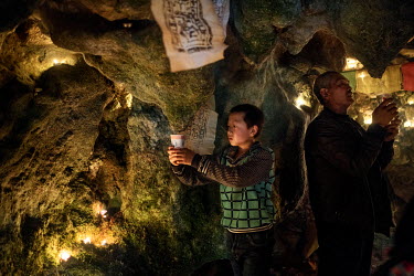 Local Nu, Lisu and Tibetan people celebrate the Fairy Festival and arrival of spring by collecting water dropping from stalactites in a sacred cave and making an offering at a Tibetan Buddhist altar.
